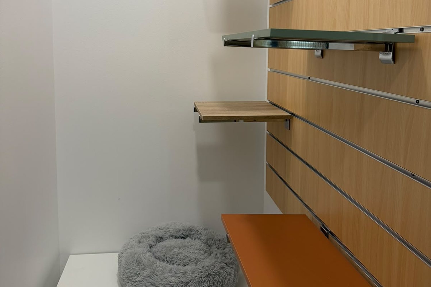 Interior de uma suite com prateleiras a várias alturas e cama macia cinzenta